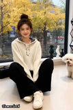Woman sitting on a floor with a small dog in a room with large windows showing trees outside.
