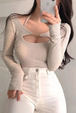 Person wearing a beige ribbed long-sleeve top with cut-out design and white pants.