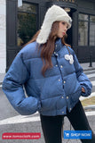 Woman wearing a blue puffer jacket with a white fur-lined hood on a street.