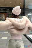 Person wearing a pink beanie and sweater in an indoor setting