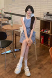 Woman in a checkered dress sitting in a cafe holding a drink.