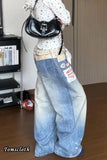 Person wearing a white blouse with black polka dots and blue jeans with patches, holding a black handbag.
