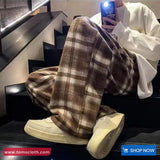 Person wearing plaid pants and white sneakers sitting on stairs, with a phone in hand.
