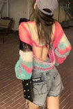 Person wearing a colorful crochet sweater and denim shorts in an indoor setting.