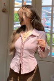 Woman wearing a pink blouse with ruffled details in a room with a window view.