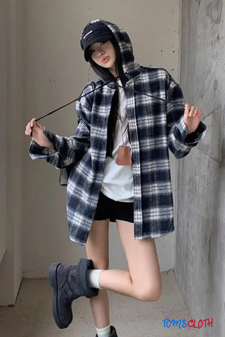 Person wearing a plaid shirt and black cap in an indoor setting