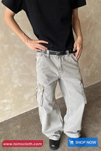 Person wearing light gray cargo pants with a plain background