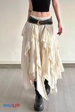 Person wearing a white ruffled skirt with a black belt and black boots on a plain background