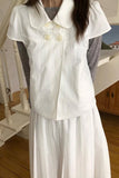 Person wearing a white dress with a collar in an indoor setting