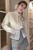 Person wearing a white blouse with lace details in an indoor setting