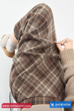 Person wearing a plaid fabric over their head with a visible brand logo at the bottom.
