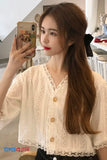 Woman taking a mirror selfie wearing a beige lace blouse with buttons.