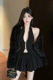 Woman in a black outfit with a fur coat holding a handbag.