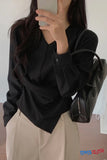 Person wearing a black shirt and beige pants holding a black handbag.