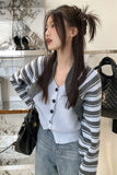 Woman wearing a striped cardigan and light blue top in an indoor setting.