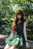Woman in a green dress standing by a pond with trees in the background