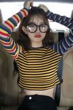 Person wearing a yellow and black striped shirt with colorful sleeves inside a vehicle.