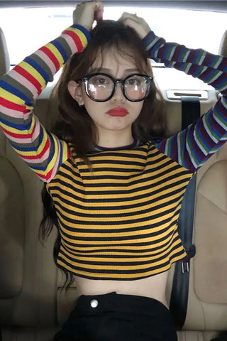 Person wearing a yellow and black striped shirt with colorful sleeves inside a vehicle.