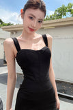 Woman wearing a black dress standing outdoors with a building and trees in the background