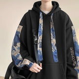 Black hoodie with blue and beige patterned sleeves worn by a person.