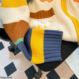 Colorful striped sweater draped over a chair with a geometric floor pattern in the background.