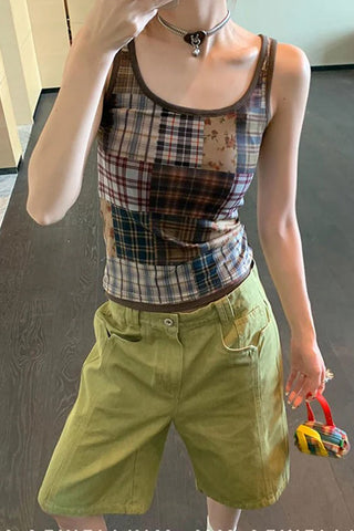 Person wearing a plaid tank top and green shorts, holding a colorful toy.