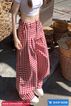 Person wearing red and white checkered pants with a white top, standing outdoors.