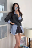 Woman taking a mirror selfie wearing a gray sweater over a striped shirt and black skirt.