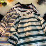 Three striped shirts in different colors on a textured surface.