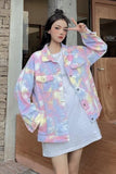 Person wearing a pastel tie-dye jacket standing outside a building.
