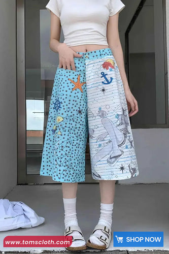 Person wearing a white top and colorful pants with patterns, standing indoors.