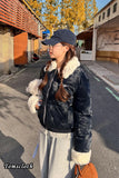 Person wearing a black coat with white fur trim, holding a plush toy, on a street.