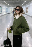 Woman in a green jacket with a white collar in a modern indoor setting