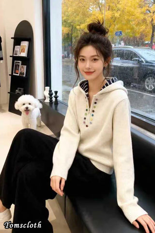 Woman in a white hoodie sitting on a bench with a dog in the background