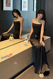 Woman in a black dress sitting on a counter with 'TOMI CLOTH' branding.