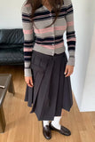 Person wearing a striped sweater and dark skirt indoors.