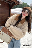 Woman in a snowy landscape wearing a beige coat and holding a handbag.