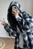 Person wearing a plaid hoodie taking a mirror selfie indoors.