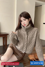 Woman wearing a brown knitted cardigan sitting on the floor with a handbag.