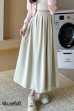 Person wearing a long beige skirt in front of a washing machine.