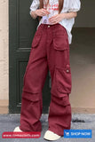 Person wearing maroon cargo pants standing against a door.
