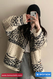 Person wearing a patterned cardigan taking a selfie against a plain background