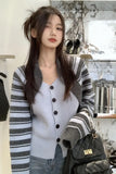 Woman wearing a striped cardigan and holding a black backpack indoors.