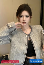 Woman wearing a gray jacket with a blurred background