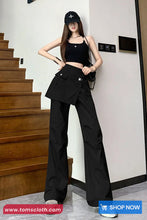 Woman in black outfit standing on a staircase with 'tomscloth.com' branding.