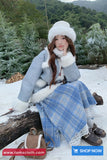 Woman in winter clothing sitting on a log in a snowy forest, with 'Toms Cloth' branding.