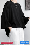 Person wearing a black oversized shirt and white pants on a plain background with 'tomscloth.com' branding.