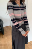 Person wearing a striped sweater with pink and navy accents in an indoor setting.