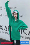 Person wearing a green oversized sweater with a blurred background