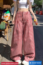 Person wearing red and white checkered pants on a street.